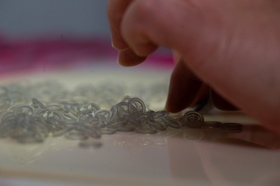 Nahaufnahme einer Hand, die kleine durchsichtige Silikonringe sortiert