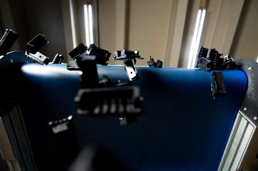 Gummiformteile, die am Ende eines Fließbands nach unten in Richtung Kamera fallen